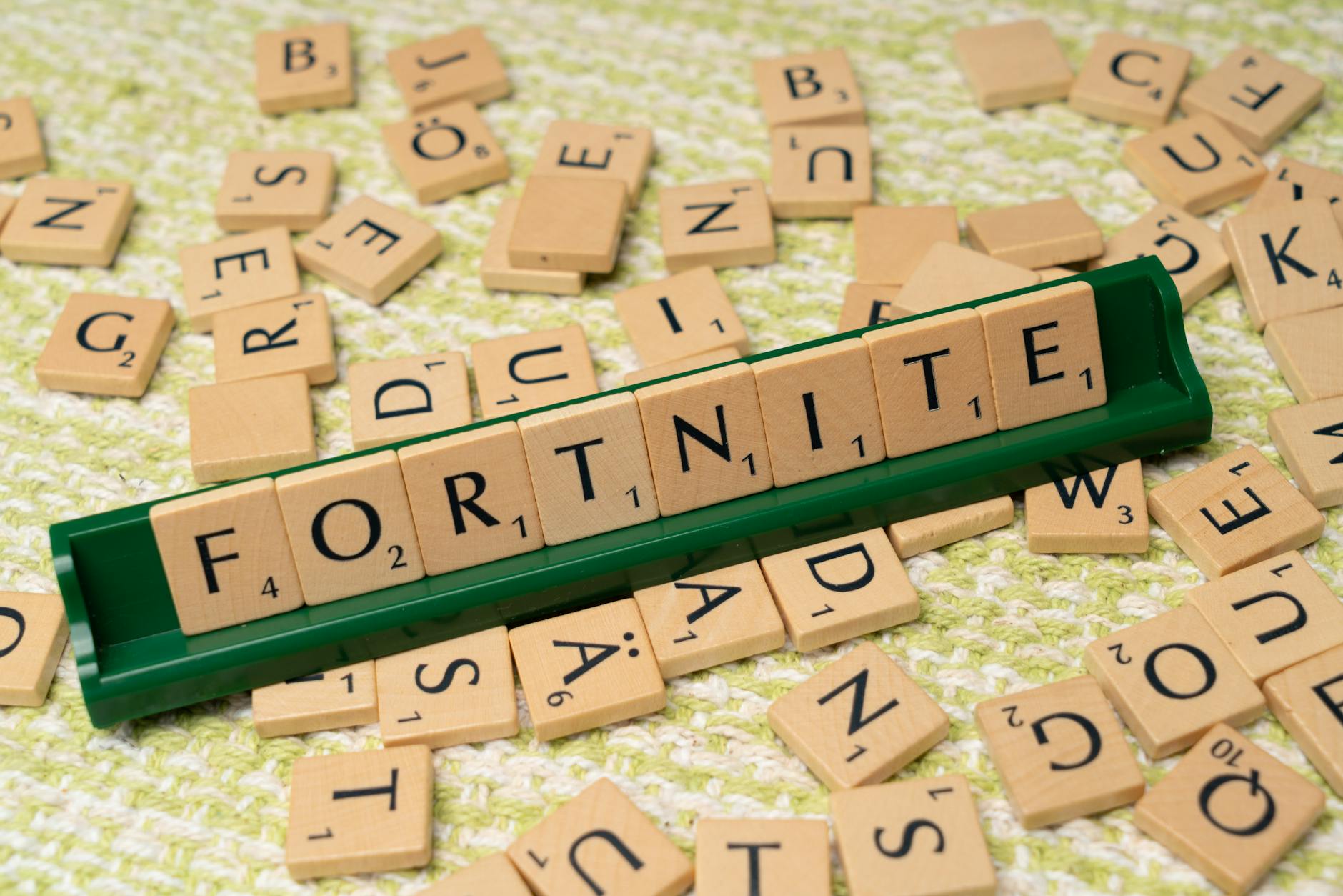 Kostki Scrabble układające się w napis Fortnite na jasnym tle