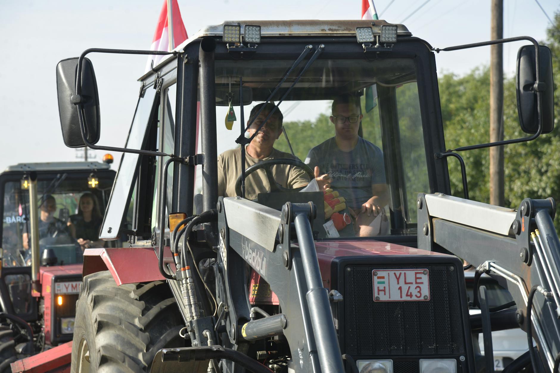 Rolnicy prowadzą dwa traktory na polu w słoneczny dzień