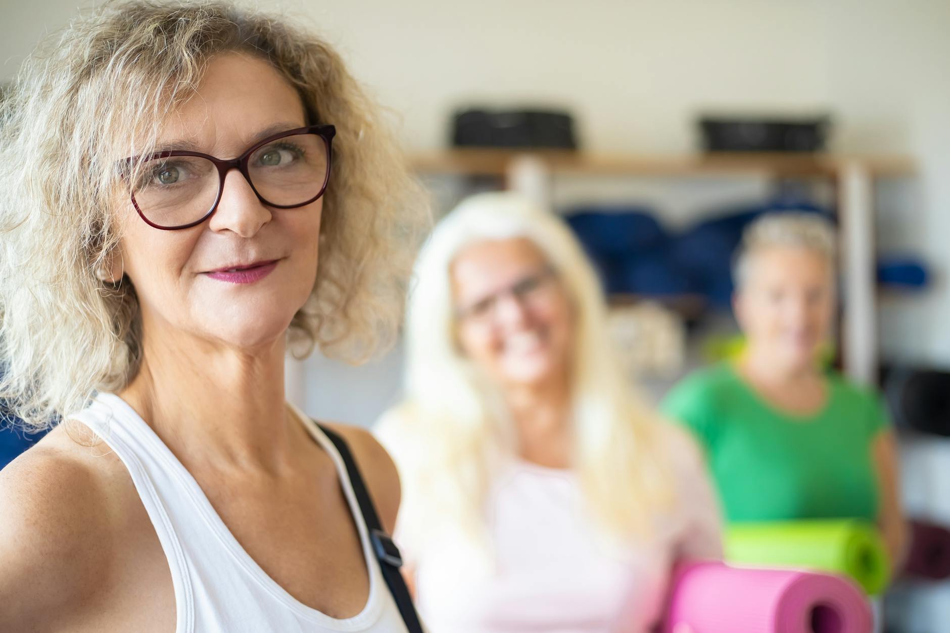 Starsze kobiety ćwiczą na matach podczas grupowych zajęć fitness