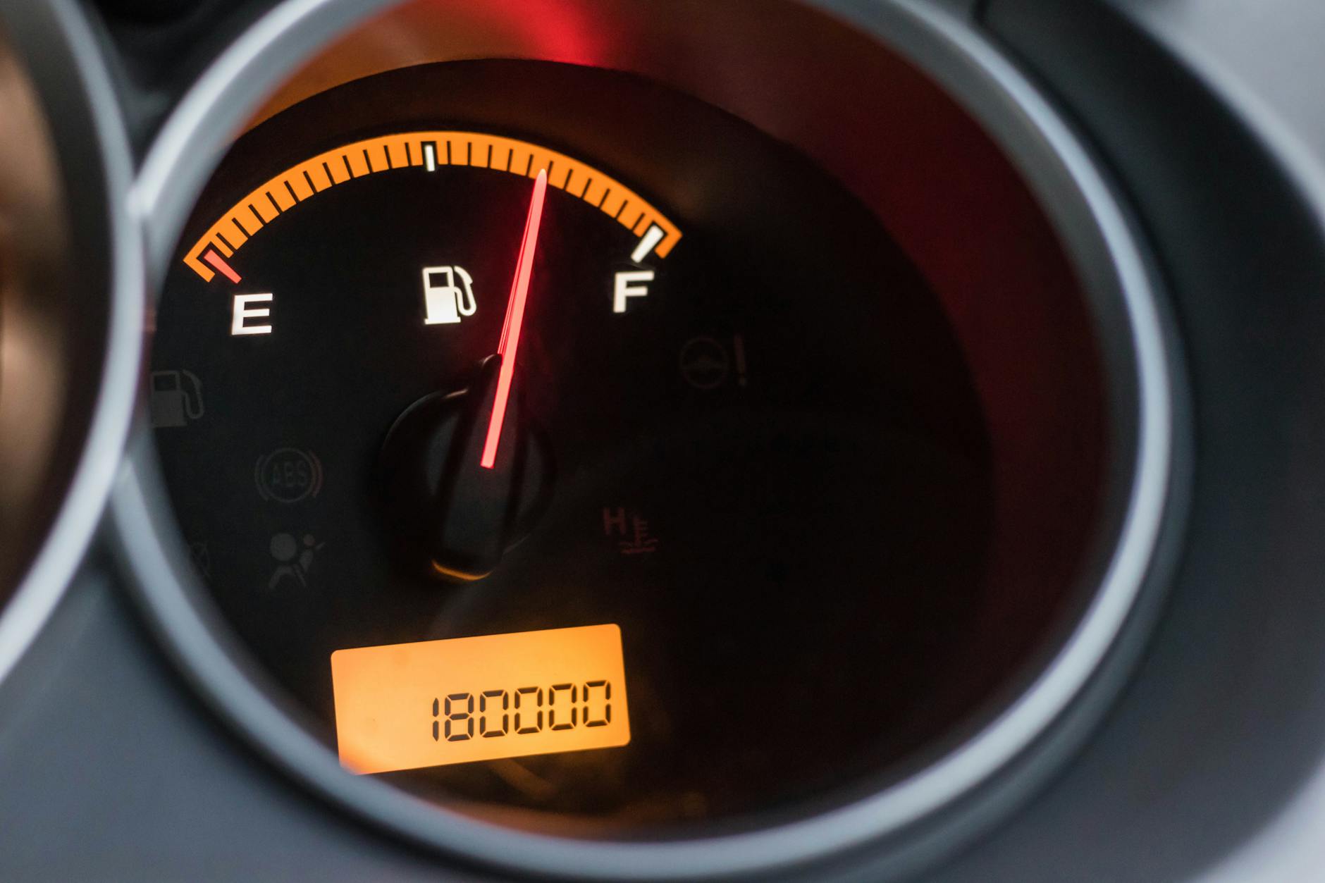 Zbliżenie na wskaźnik paliwa w aucie z pełnym bakiem i licznikiem przebiegu